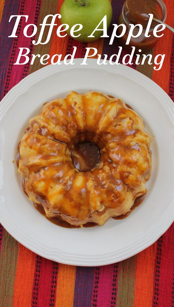 an apple bread pudding on a white plate with caramel sauce and apples in the background