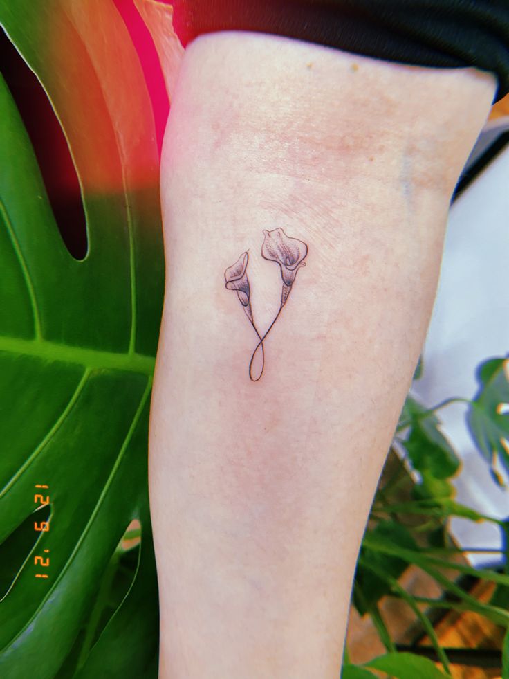 a woman's leg with a small tattoo of two flowers on the left side