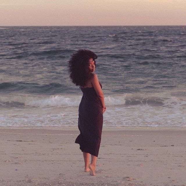 a woman standing on top of a beach next to the ocean