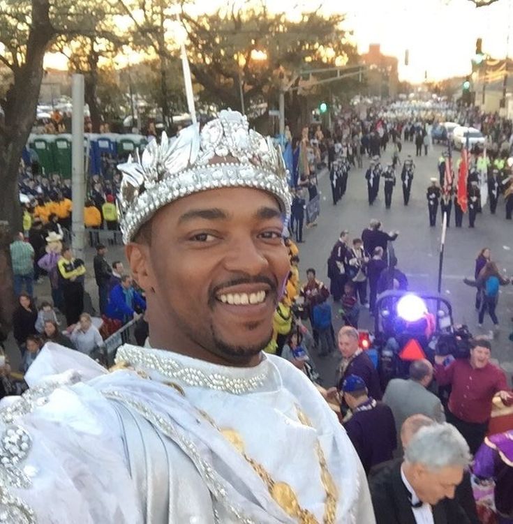 a man wearing a crown and standing in the middle of a street surrounded by people