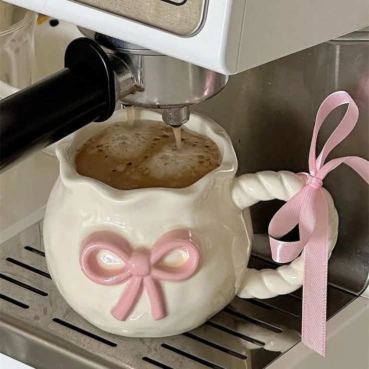 a coffee pot with a pink bow on it