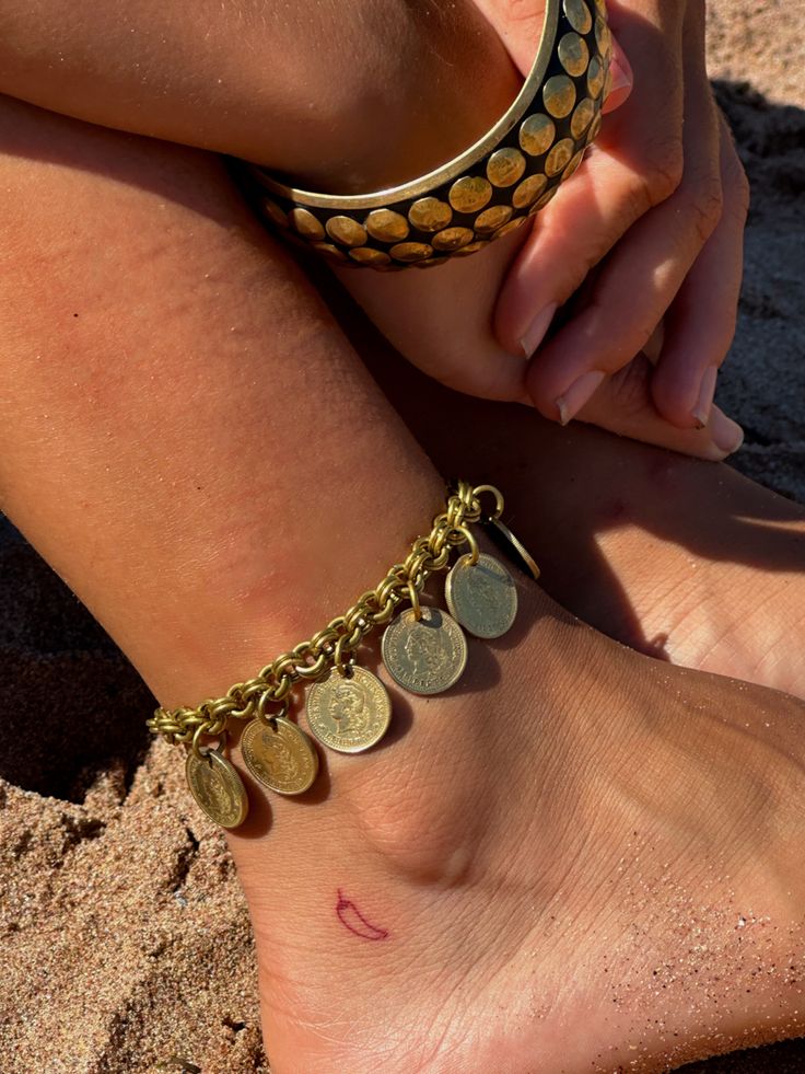 a close up of a person's foot with gold coins on it and a coin bracelet