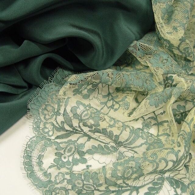 a green and white scarf sitting on top of a table next to a piece of cloth