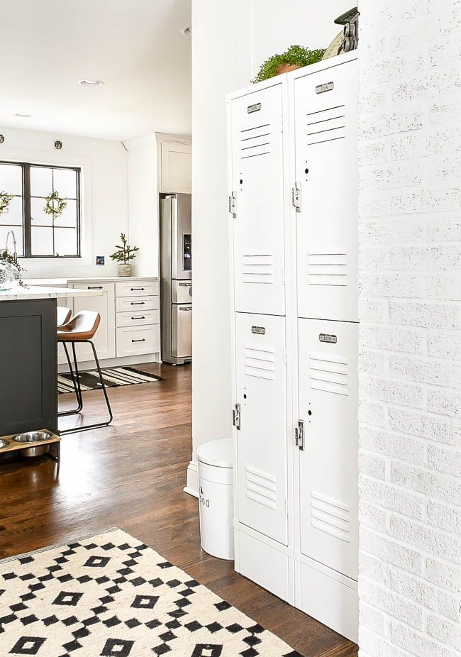 a kitchen with white cabinets and wood floors next to a black and white area rug