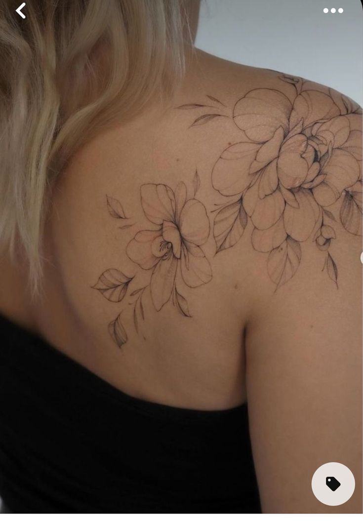 the back of a woman's shoulder with flowers tattooed on her left arm and chest