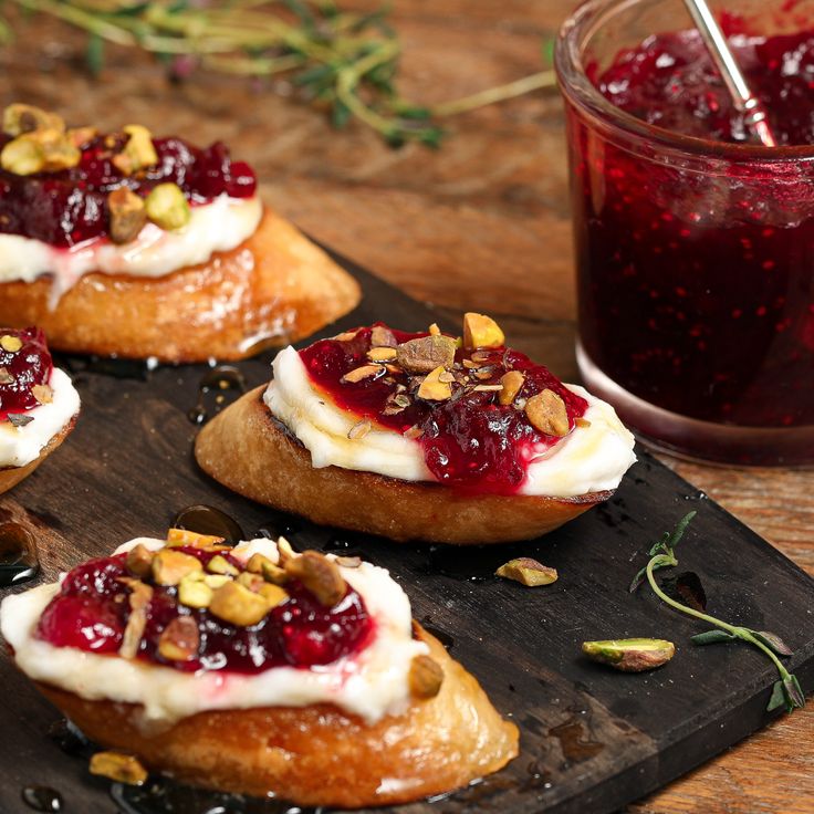 four cranberry and almond pastries on a wooden tray with a glass of juice