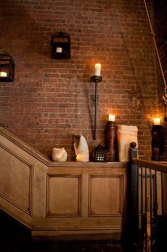 candles are lit on the side of a brick wall next to a set of stairs