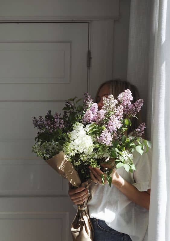 a woman holding a bouquet of flowers in front of a garage door with the sun shining through