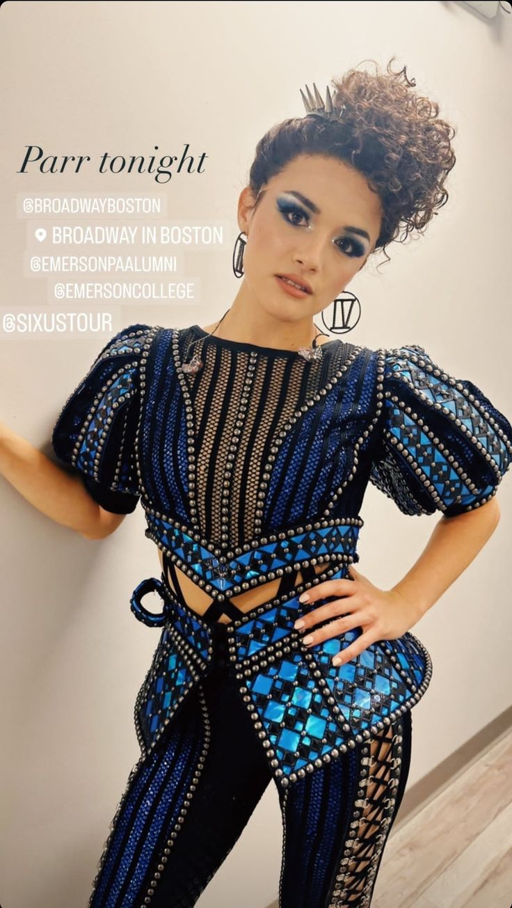 a woman in blue and black outfit standing next to a wall