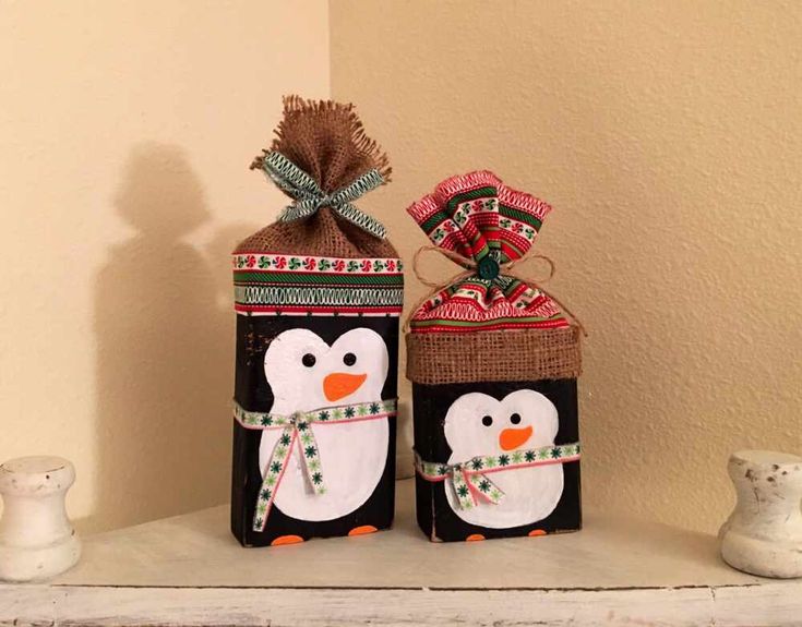 two snowmen with hats and scarfs are sitting on a shelf next to each other