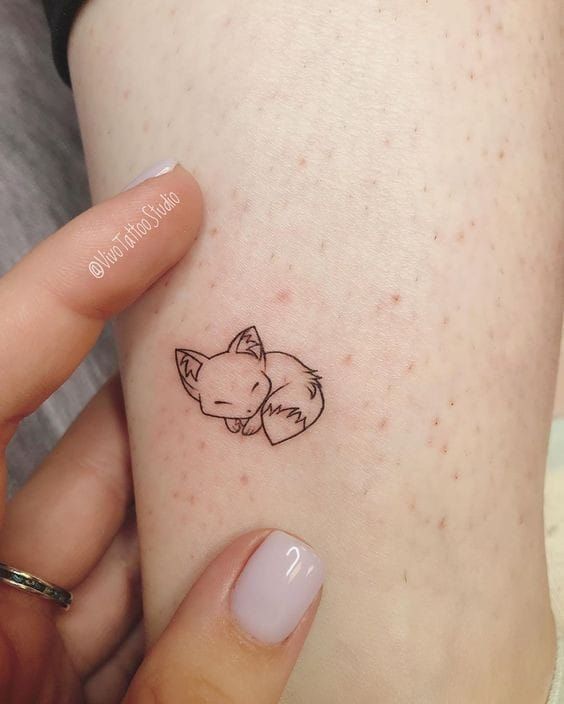 a woman's arm with a small tattoo of a cat on the left side