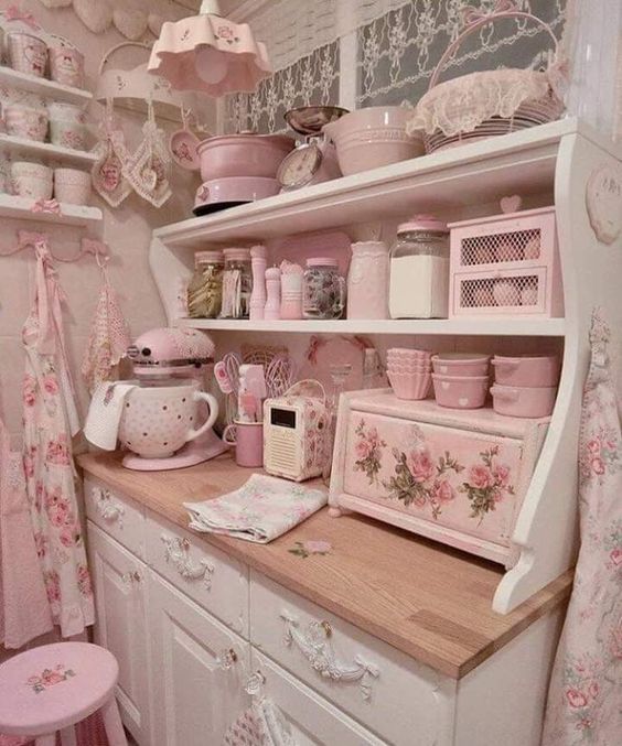 a pink kitchen with lots of dishes on the shelves