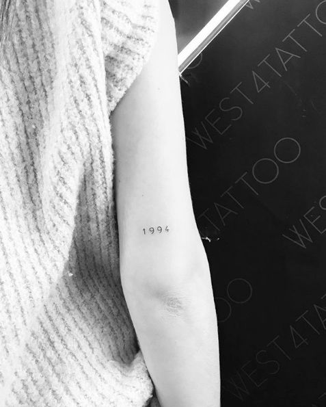 a woman with a tattoo on her arm that reads,'year 1994'in black and white