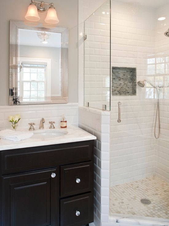 a bathroom with a walk in shower next to a white sink and black cabinetry