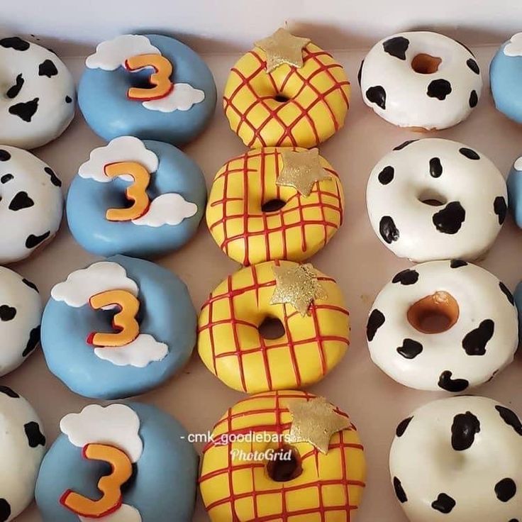 there are many decorated doughnuts with numbers on them in the box and one has a dog