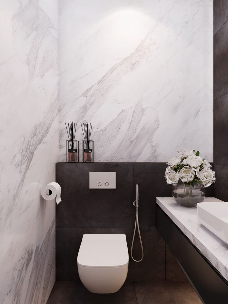 a white toilet sitting in a bathroom next to a counter with flowers and candles on it