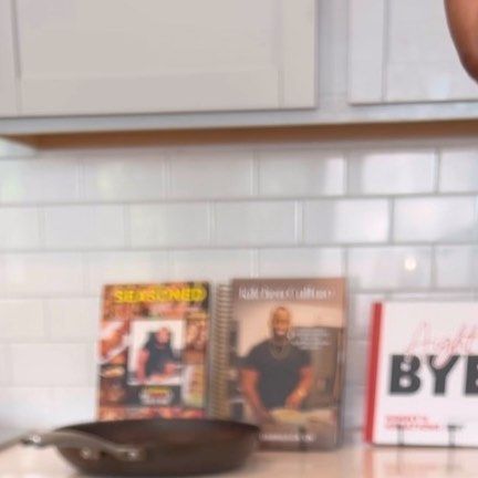 a pan sitting on top of a kitchen counter next to a frying pan and cookbooks