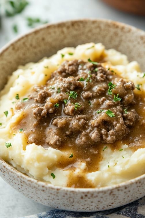 a bowl filled with mashed potatoes topped with meat and gravy