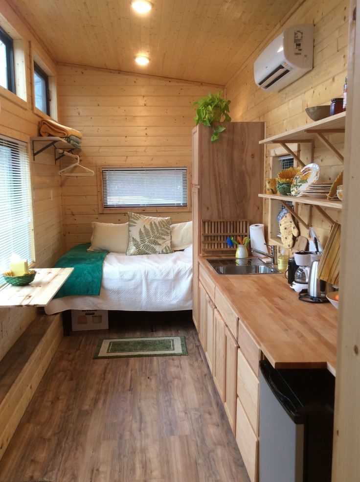 a small bedroom with wooden walls and flooring in a tiny cabin style home on wheels