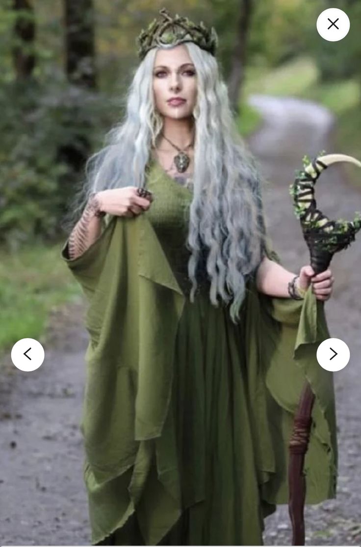 a woman with long white hair wearing a green dress and holding a flower in her hand