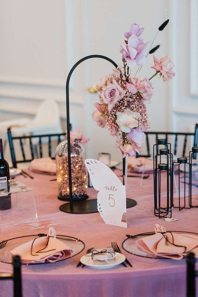 the table is set with pink flowers and place settings for guests to sit down at