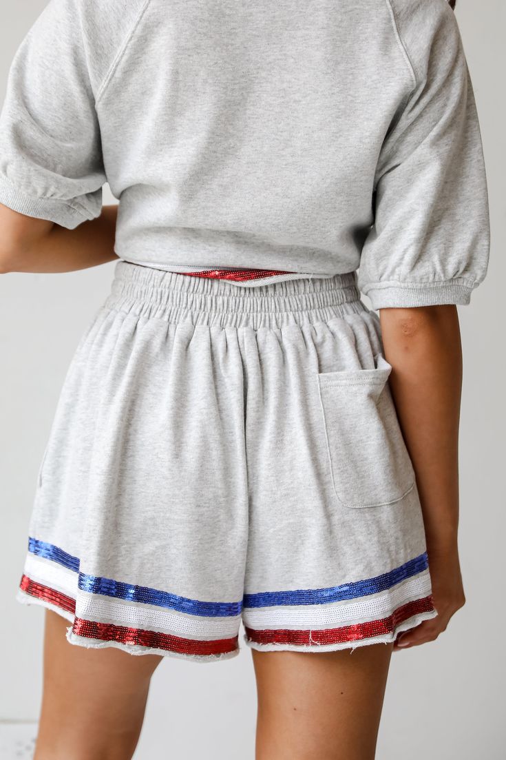 Step into casual chic with the USA Heather Grey Sequin Shorts! These cute shorts are embellished with eye-catching red, white, and blue sequin stripes on the hems. These shorts combine comfort and style, featuring a soft, breathable fabric and a relaxed fit perfect for warm weather. The vibrant sequin stripes add a playful and patriotic touch, making these shorts ideal for 4th of July festivities or any casual outing. With an elastic waistband, they offer a customizable fit for all-day comfort. Casual Spring Sequin Shorts, Casual Sequined Bottoms For Summer, High-waisted Sequin Shorts For Summer, Sequin High-waisted Shorts For Summer, 4th Of July Cotton Shorts, Cute Matching Sets, Casual Kimono, Cute Matching, Shorts Cute