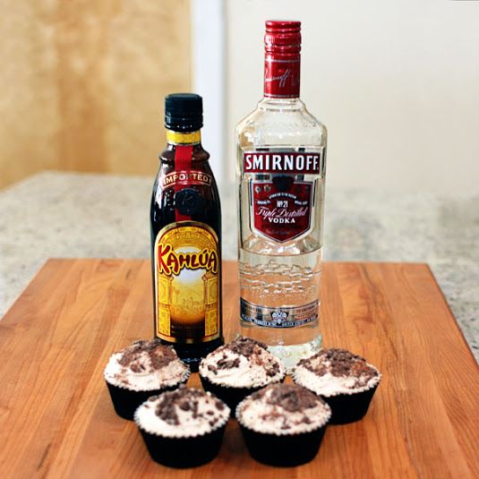 two bottles of vodka sitting next to each other on a wooden cutting board with salt and pepper