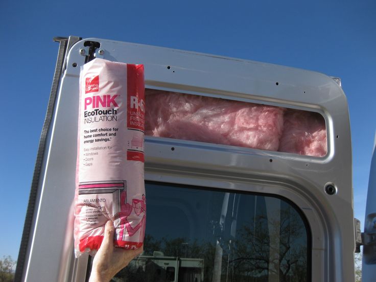 a person is holding up a pink product in the back of a truck with its door open