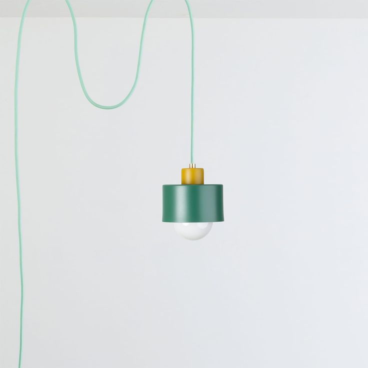 a green lamp hanging from a ceiling in a room with white walls and flooring