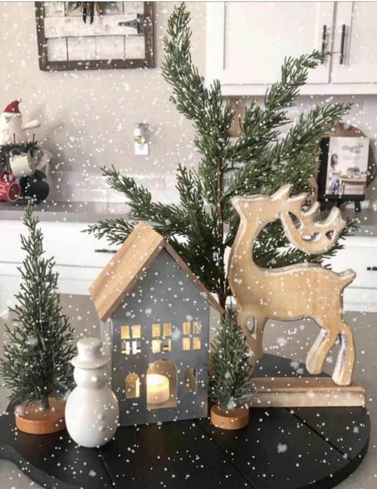 a christmas scene with a house, tree and deer on a black table in the kitchen