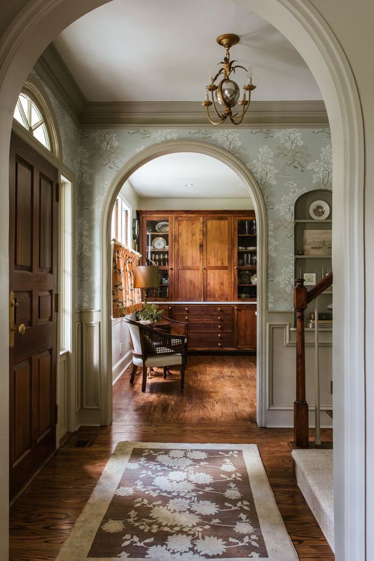 an archway leads to the dining room and living room in this country house with wood flooring