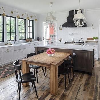 a large kitchen with wooden floors and white cabinetry, along with an island table surrounded by black chairs