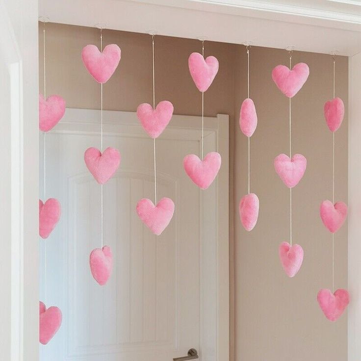 pink hearts hanging from the ceiling in front of a door with white trimmings