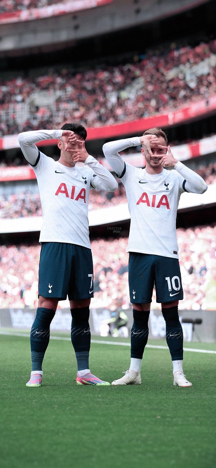 two soccer players are standing in front of the stands with their hands behind their heads