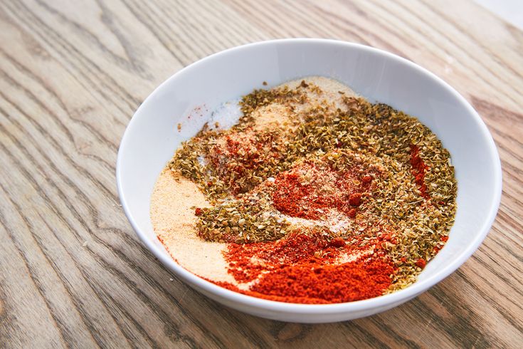 a white bowl filled with spices on top of a wooden table