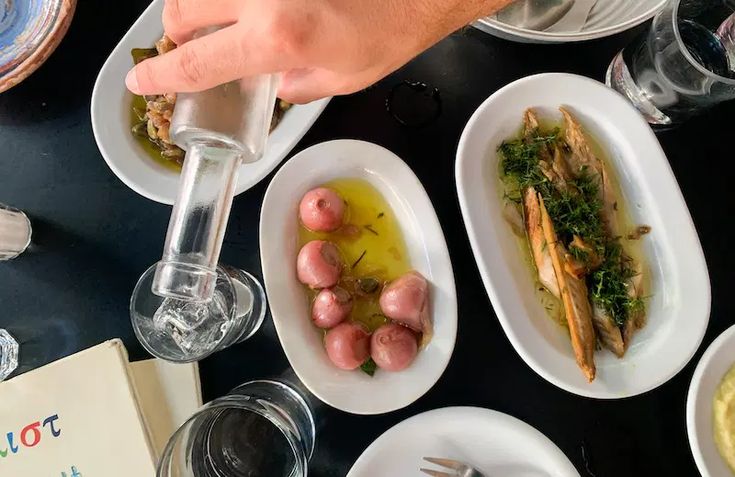 a table topped with white plates filled with different types of food and wine glasses next to each other