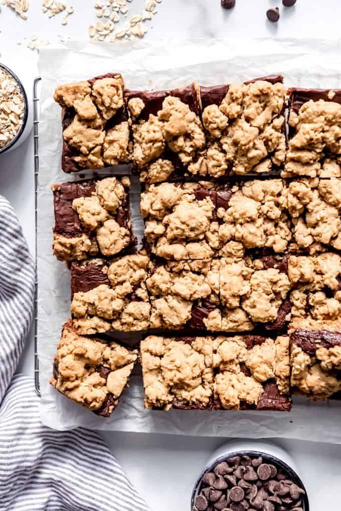 chocolate chip cookie bars cut into squares and placed on parchment paper next to bowls of oatmeal