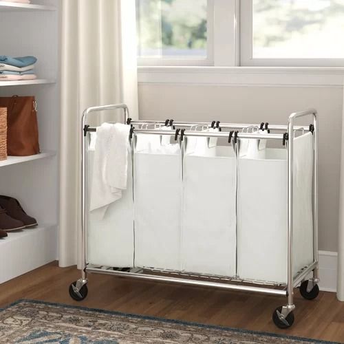 a white laundry sorter sitting on top of a wooden floor next to a window