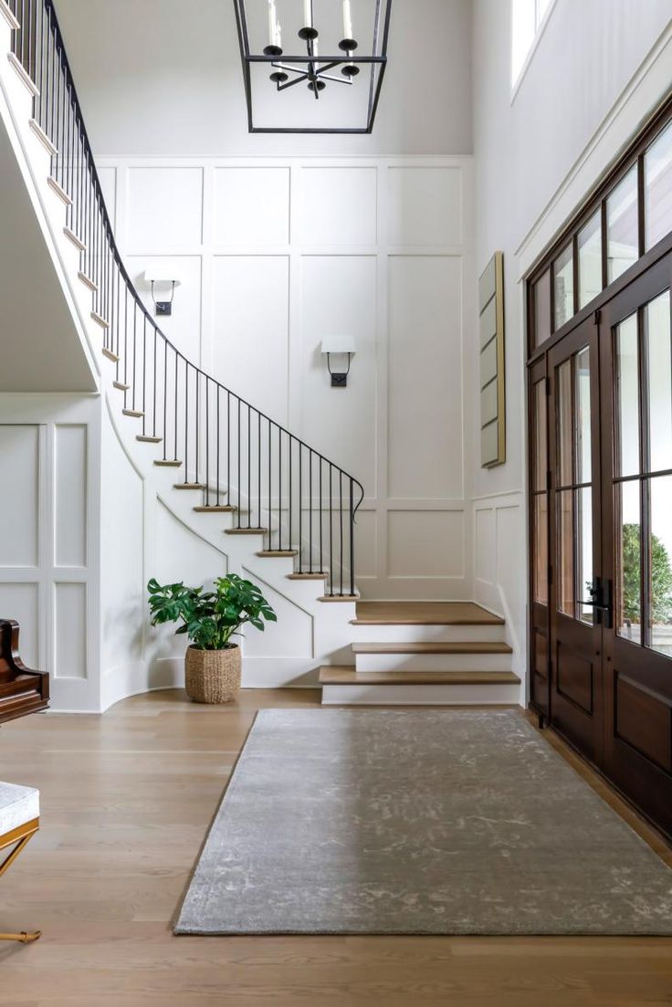 an entryway with stairs, potted plant and chandelier in the background