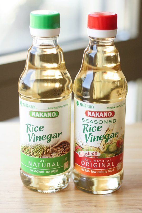 two bottles of vinegar sitting on top of a wooden table