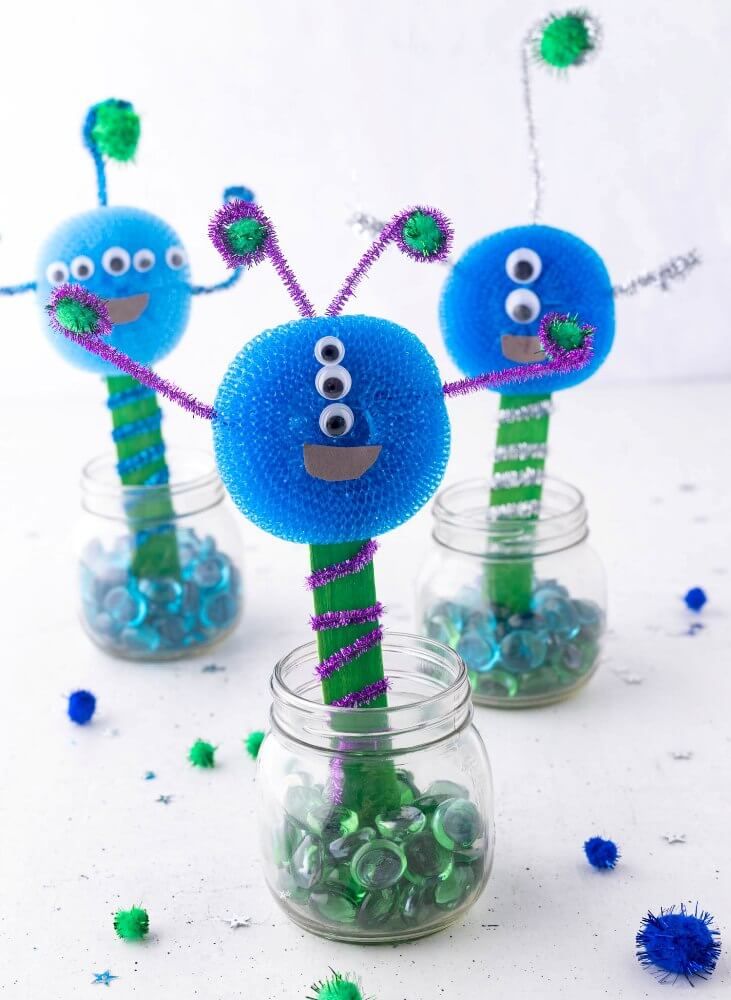 three glass vases filled with blue and green decorations