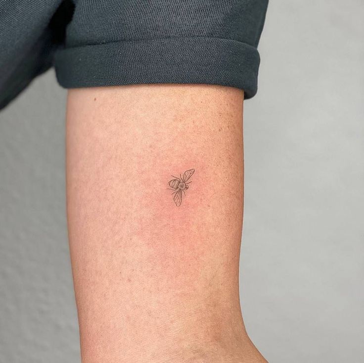 a small bee tattoo on the left arm