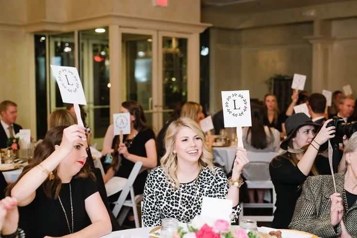 a group of women holding up signs in front of their faces at a dinner table