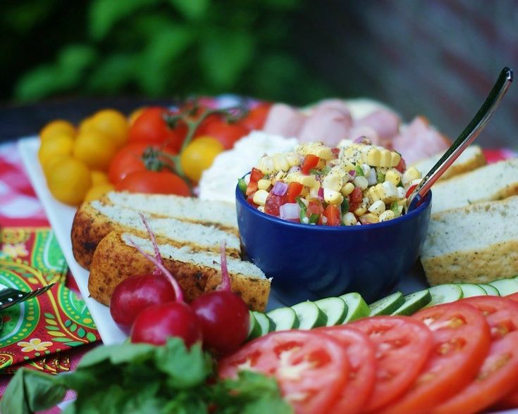 a platter filled with bread, tomatoes, cucumbers and corn