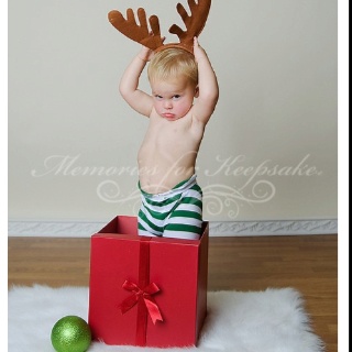 a young boy is sitting in a box with reindeer antlers on it's head