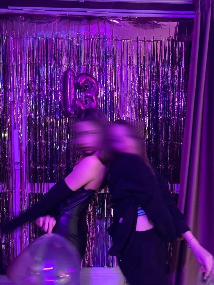 a man and woman are dancing in front of purple tinsel curtained backdrops