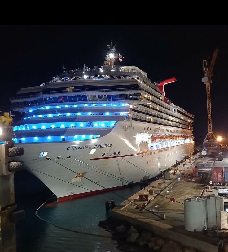 a large cruise ship docked at a dock in the night with lights on it's side