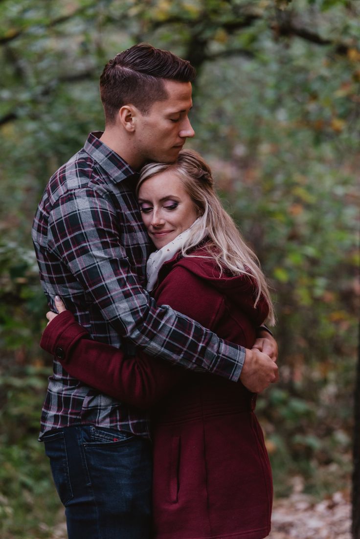 a man and woman hugging in the woods during their fall engagement session at stone mountain state park