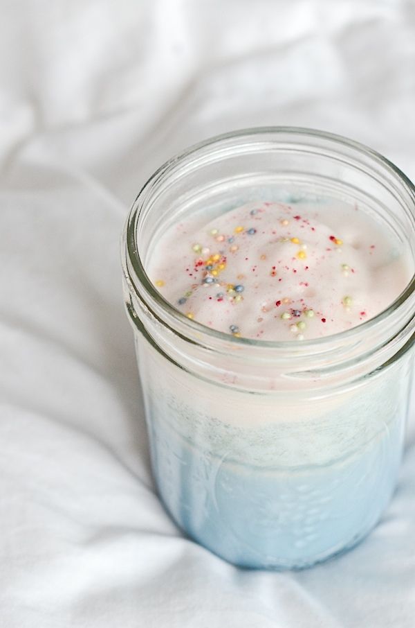 a glass jar filled with liquid and sprinkles on top of a white sheet