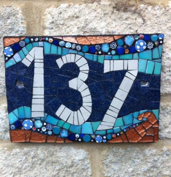 a blue and white mosaic tile number sign on a stone wall with the number twenty seven in it